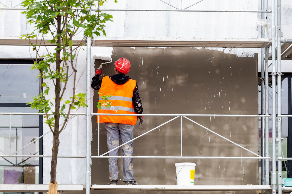 a man doing a paint job outside a property