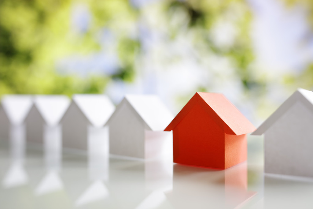 A row of miniature houses, all painted white except for one in red