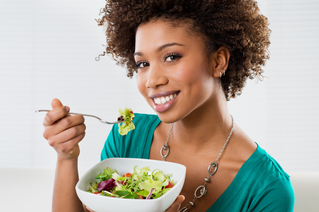 African American Woman Eating Salad At Home