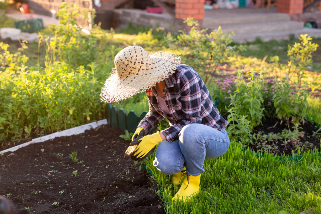 a woman wearing a hat while planting in the garden