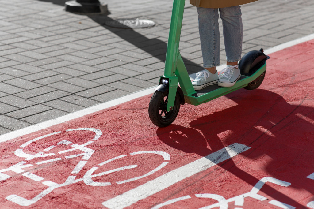 Woman riding electric scooter along red bike lane or road with signs of bicycles on street
