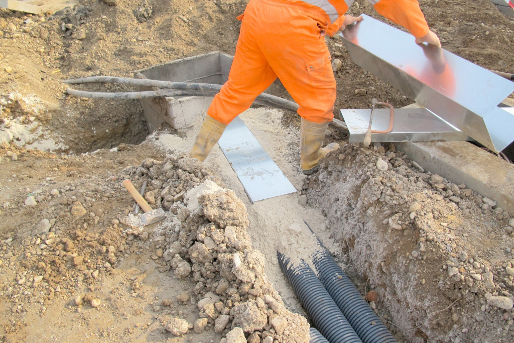 A worker covering pipes in the soil