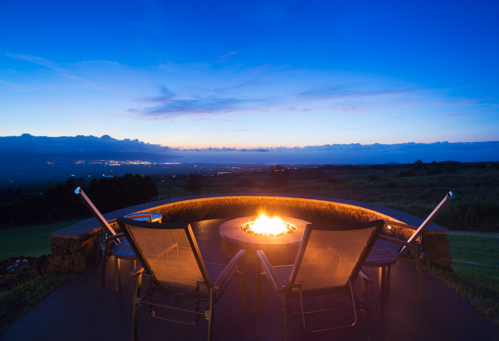 A fire pit surrounded by chairs at night