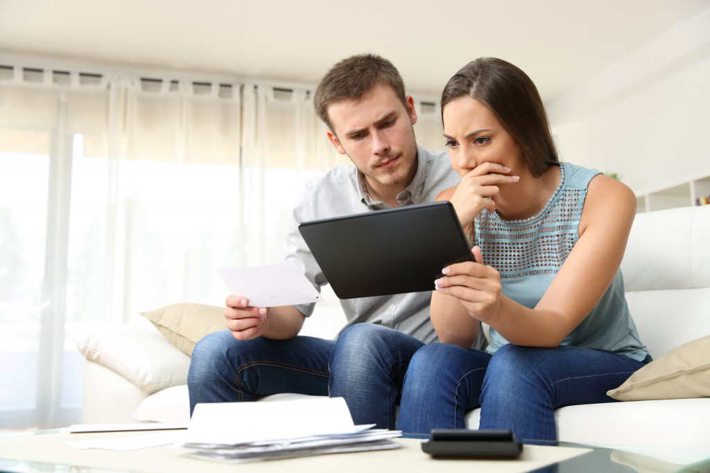 man and woman budgeting using their laptop and financial documents in the living room