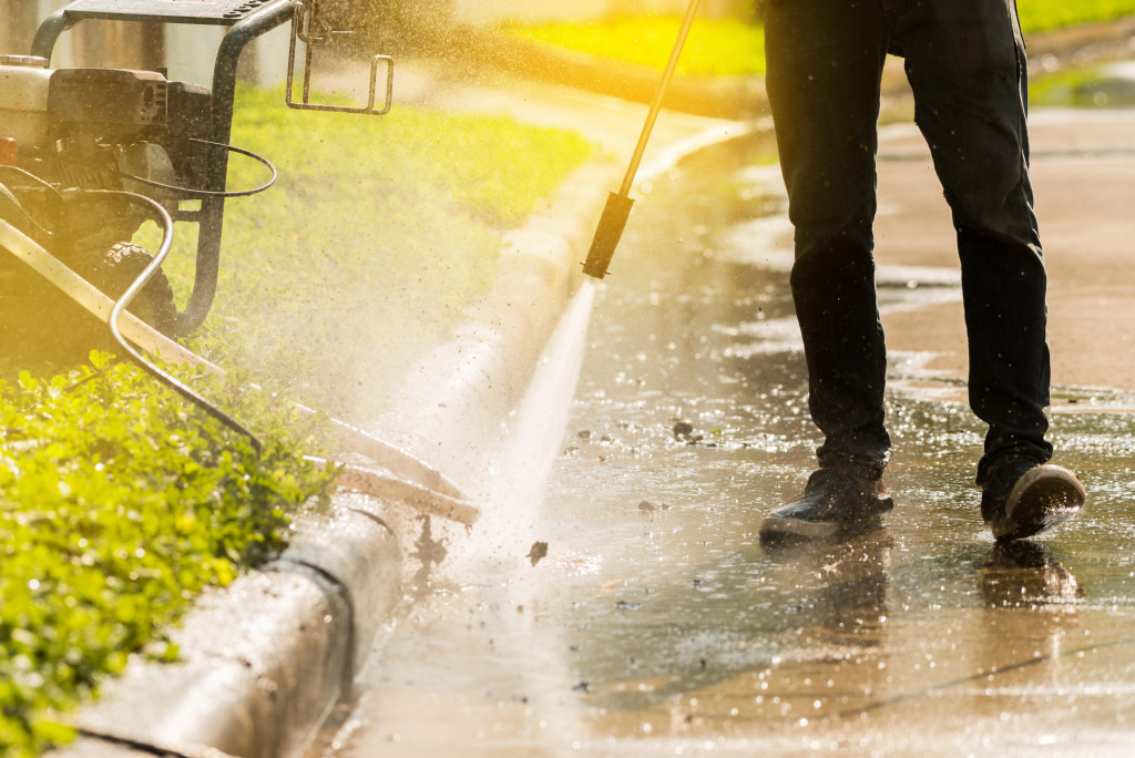 Professional using a power washer to clean the front of a house.