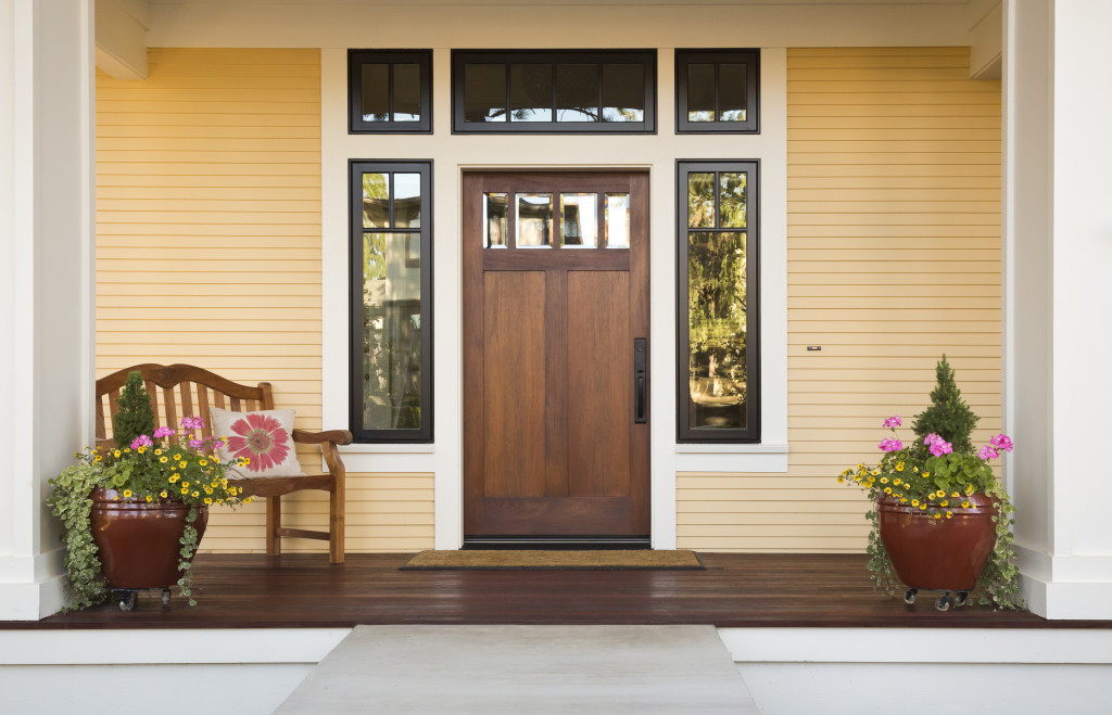 Elegant front door of a house with plants and a bench.