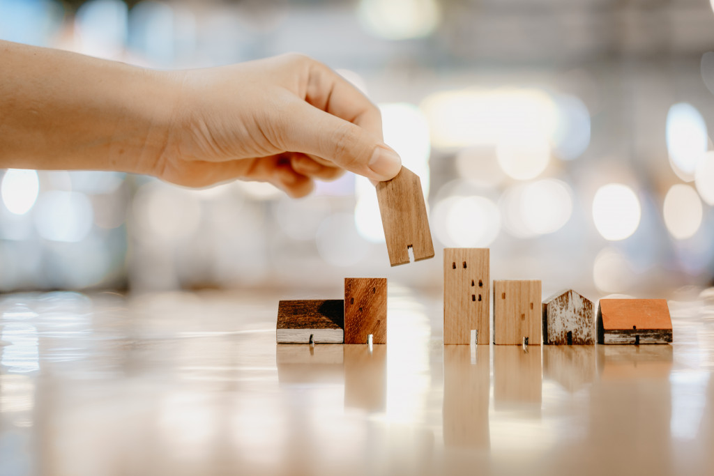 person using model wooden houses in a line